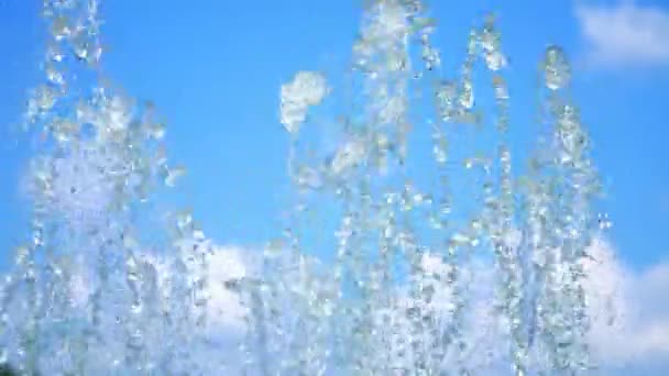 Fontaine, éclaboussures, éclaboussures d'eau contre le ciel bleu. Eau de fontaine sèche gros plan. Des gouttes d'eau scintillent au soleil. été, journée ensoleillée. Eau sortant d'une fontaine . — Video