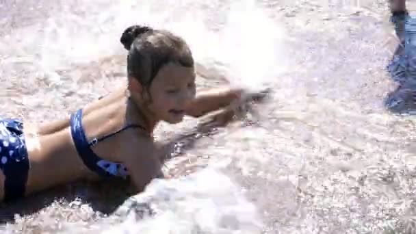 Lächelndes, glückliches achtjähriges Mädchen im Badeanzug, das Spaß beim Plantschen im Stadtbrunnen hat, im Freien, im Park, Sommer, heißer sonniger Tag im Urlaub. — Stockvideo