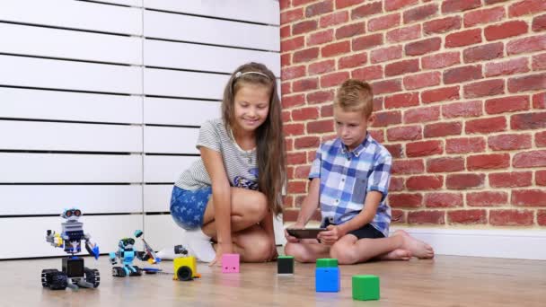 Siebenjährige Jungen und Mädchen spielen elektronische Roboter, Autos, modernes Spielzeug am Radio. neue Technologien in der Spiele-Industrie für Kinder. Kleine Genies — Stockvideo