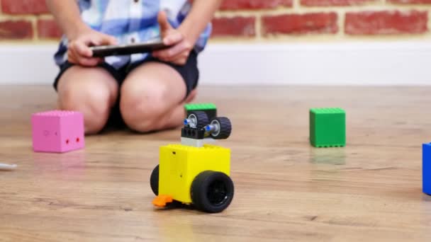 Close-up, radiografisch bestuurde robot beweegt op vloer, weinig genieën, kinderen spelen elektronische robots, auto's, moderne speelgoed op RadioControle. nieuwe technologieën in de gamingindustrie. — Stockvideo