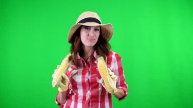 Mısır koçanı Studio yeşil arka plan üzerinde elinde tutan gülümseyen kadın çiftçi kareli gömlek ve şapka, portresi. corncobs, gıda ile cinsel ilişki.