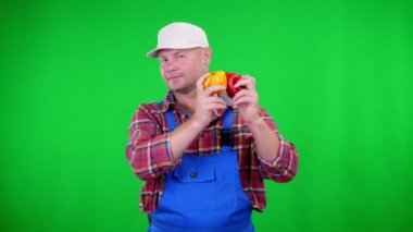 ekose gömlek ve şapka gülümseyen erkek çiftçi tatlı biber, biber, marakas gibi Chromakey, yeşil arka plan sallayarak tutar. tablonuza sağlıklı gıda kavramı