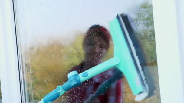 Γκρο πλαν, για το γυαλί παράθυρο είναι αντανακλάται χαμογελώντας Καυκάσιος όμορφη γυναίκα, στα γάντια, καθαρισμός, πλύσιμο παραθύρων με ειδικό σφουγγαρίστρα, με πολύ αφρό στο ποτήρι. Υπηρεσία καθαρισμού — Αρχείο Βίντεο