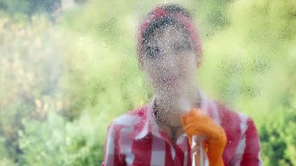 Widok przez okno, uśmiechając się piękna kobieta w rękawice, czyszczenie okna przez rozpylanie produkty czyszczące, przy użyciu detergentu i szmata. pracownik, czyszczenie usługi lub gospodyni — Wideo stockowe