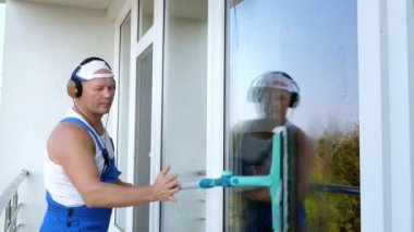 Beyaz çekici adam cep telefonu kulaklık ile müzik dinlemek, temizlik hizmet işçisi, mavi tulum, Temizleme, pencere yıkama tarafından özel paspas,