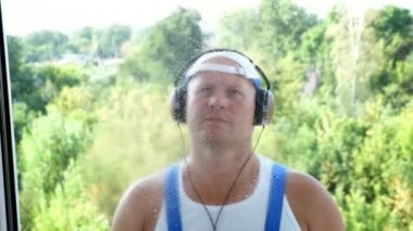 Görünümü penceresinden, çekici erkek temizlik hizmet işçisi, kulaklık, temizlik ürünleri, deterjan, kullanarak püskürtme tarafından pencere Temizleme ile paçavra. müzik,