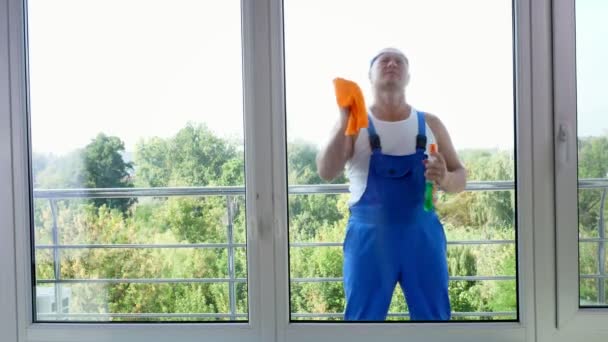 View through window, attractive male cleaning service worker, in blue overalls and in blaser, Cleaning Window by spraying Cleaning Products, using detergent, rag — Stock Footage View through window, attractive male cleaning service worker, in blue overalls and in blaser, Cleaning Window by spraying Cleaning Products, using detergent, rag Royalty Free Stock Video
