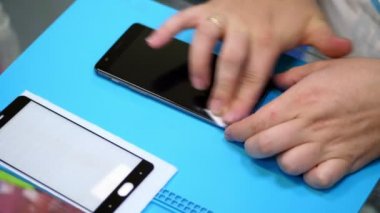 holding ve bir cep telefonu ekran temizleme erkek ellerini koymak, geçerli bir smartphone, bakım destek ve tamir servisi korumak için koruyucu bir temperli cam