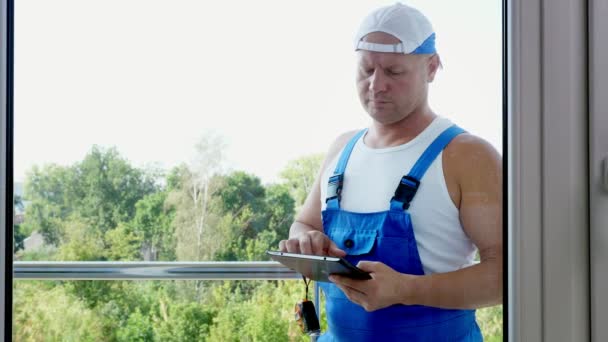 Attractive Construction worker makes notes in tablet. service man installing window — Stock Footage Attractive Construction worker makes notes in tablet. service man installing window Royalty Free Stock Video