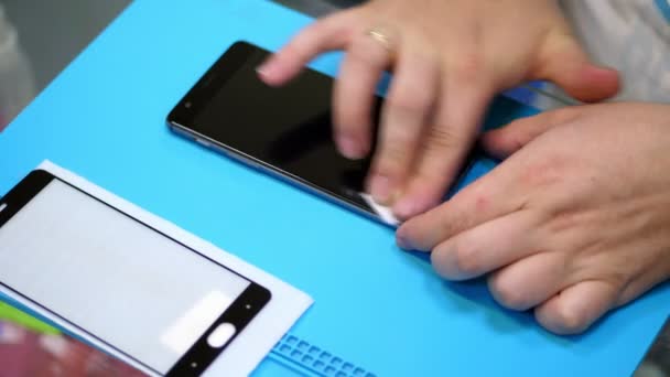 Male Hands holding and cleaning a mobile phone screen to put on, apply a protective tempered glass to Protect a smartphone, Maintenance support and repairing service — Stock Video