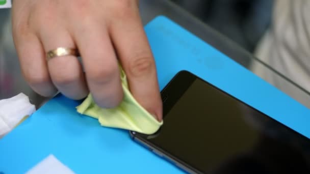 Mannelijke handen houden en schoonmaken van het scherm van een mobiele telefoon te zetten, gelden een beschermende gehard glas ter bescherming van een smartphone, alimentatie en reparatie service — Stockvideo