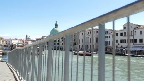 Venedig, Italien - 7 juli 2018: utsikt över Venedig genom stängslet av bron, canal Grande, vapareto flötena på vatten, småbåtar, gondoler segla, en varm sommardag, — Stockvideo