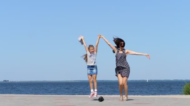 Na plaży Mama i córka piękna brunetka w sukienkę i dziewczyna nastolatek dziecko, taniec, słuchanie muzyki z mini muzyki bluetooth przenośne głośniki w gorący letni dzień — Wideo stockowe