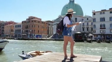 Venice, İtalya - 7 Temmuz 2018: Venedik Haritası eski binalar Venedik arka planı elinde tutan turist kadın şapka, şort, onun omuzlarında bir sırt çantası