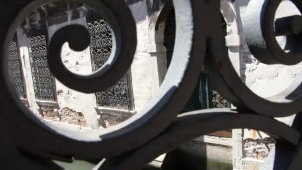 VENICE, ITÁLIA - JULHO 7, 2018: vista através da obra de aberturas, ponte forjada para o edifício antigo, de pé sobre a água do canal, com barras antigas forjadas nas janelas — Vídeo de Stock