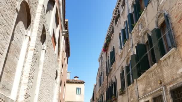 VENEZIA, ITALIA - 7 LUGLIO 2018: bellissima vecchia architettura di Venezia, una casa con vecchie persiane verdi e fiori sui davanzali delle finestre, contro il cielo blu, in una calda giornata estiva , — Video Stock