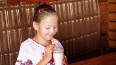 mutlu gülümseyen genç kız çocuk bir milkshake kafede içecekler. o giyinmiş Ukrayna Ulusal giysiler, nakış, vishivanka