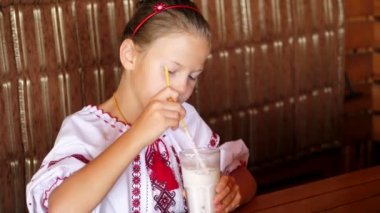 mutlu gülümseyen genç kız çocuk bir milkshake kafede içecekler. o giyinmiş Ukrayna Ulusal giysiler, nakış, vishivanka