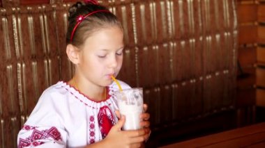 mutlu gülümseyen genç kız çocuk bir milkshake kafede içecekler. o giyinmiş Ukrayna Ulusal giysiler, nakış, vishivanka