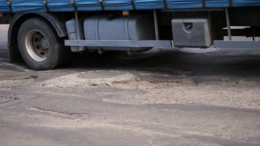 yakın çekim, çok kötü yol kapsamı, birçok çukurları, asfalt kavisli, büyük bir kamyon yavaş yavaş bayağı uzun yol bir bakıma muhtaç geçer.. yol onarım ihtiyacı.