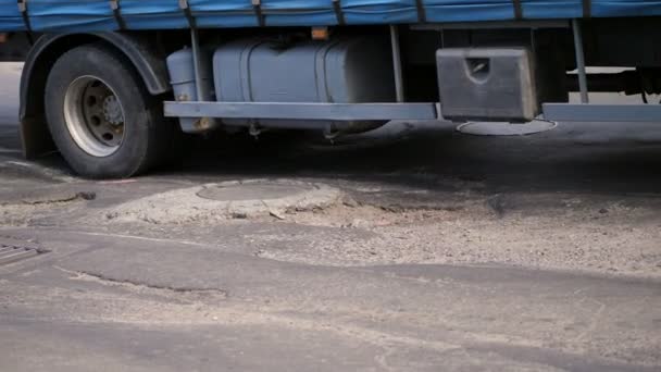 Yakın çekim, çok kötü yol kapsamı, birçok çukurları, asfalt kavisli, büyük bir kamyon yavaş yavaş bayağı uzun yol bir bakıma muhtaç geçer.. yol onarım ihtiyacı. — Stok video