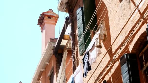 ヴェネツィア, イタリア - 2018 年 7 月 7 日: 美しい古い建築ベニス、古い緑のシャッターのある家の服に洗濯物の乾燥します。夏の暑い日に、青い空を背景, — ストック動画