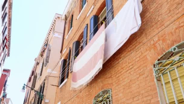 VENECIA, ITALIA - 7 DE JULIO DE 2018: hermosa arquitectura antigua de Venecia, una casa con persianas azules viejas, la ropa se seca en el tendedero. contra el cielo azul, en un caluroso día de verano , — Vídeo de stock