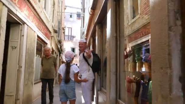 VENECIA, ITALIA - 7 DE JULIO DE 2018: un hombre con una niña caminando por las calles comerciales de Venecia, muchas tiendas, tiendas de recuerdos. Los turistas están comprando recuerdos. caliente día de verano . — Vídeos de Stock