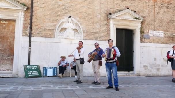 Venice, Olaszország - július 7-én 2018-ban: utcai zenészek, trió, játszik, velencei utcában szórakoztatja a turistákat — Stock videók