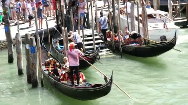 VENICE, ITALY - JULY 7, 2018: Grand Canal , gondolas full of tourists. gondoliers are waiting for tourists on special piers, stops for gondolas. hot summer day. — Stock Video