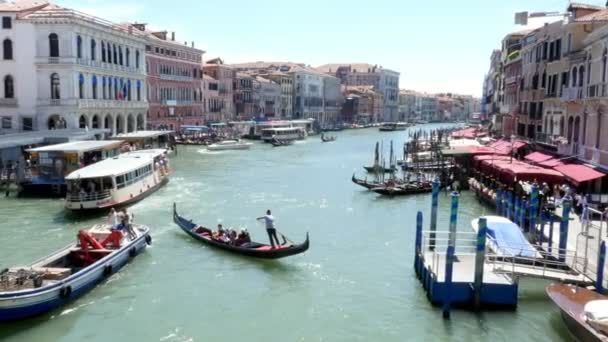 ヴェネツィア, イタリア - 2018 年 7 月 7 日: 大運河ヴェネツィア、夏の暑い日の古代の家との間。運河沿いの伝統的なヴェネツィアン ・ ゴンドラのフロートを運ぶ観光客 — ストック動画