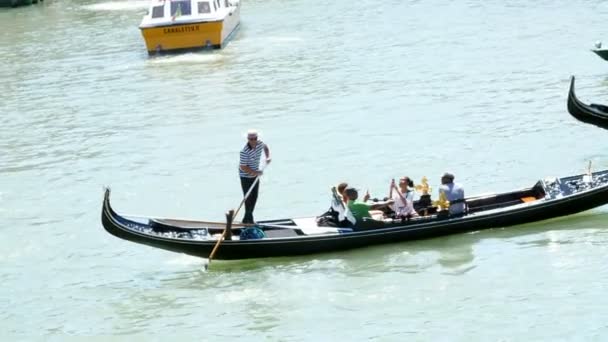 ヴェネツィア イタリア 2018 大運河ヴェネツィア 夏の暑い日の古代の家との間 伝統的なヴェネチアのゴンドラ運河に沿ってフロートを運ぶ観光客 — ストック動画