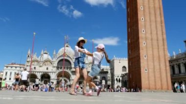 Venice, İtalya - 7 Temmuz 2018: mutlu güzel kadın ve çocuk kız, elele, Piazza San Marco, St Marks Bazilikası, bir yaz günü iplik turistler, görünüm