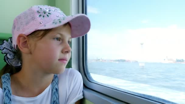 Staand, mooi meisje kind, in een roze Pet, kijkt uit het raam van het schip, bewondert het Zeegezicht — Stockvideo