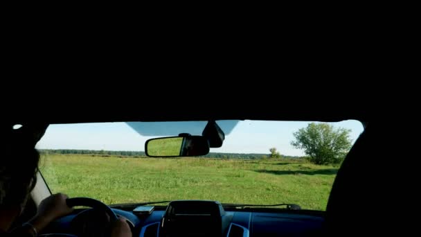 Vista desde el interior del coche a través del parabrisas. granjero cabalga a través del campo verde, examina su tierra. día de verano . — Vídeo de stock