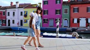 Venedik, Burano, İtalya - 7 Temmuz 2018: genç bir kadın ve bir çocuk kız aynı denim tulum, şort, Burano küçük kanal boyunca sokaklarda yürümek. sıcak yaz günü.