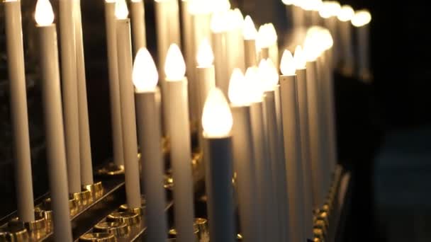 OROPA, BIELLA, ITALIA - 7 DE JULIO DE 2018: de cerca, muchas velas eléctricas encendidas en el altar de la iglesia católica. Santuario de Oropa, Santuario, en las montañas cerca de la ciudad de Biella, Piamonte, Italia . — Vídeo de stock