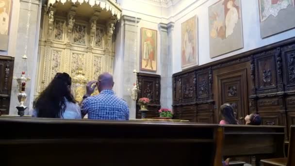 Oropa, Biella, Italien - 7 juli 2018: folk sitter på bänkar, vid altaret, i den katolska kyrkan. Helgedomen av Oropa, Sanctuary, i bergen nära staden av Biella, Piemonte, Italien. — Stockvideo