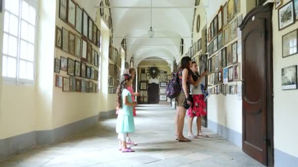 OROPA, BIELLA, ITALIA - 7 DE JULIO DE 2018: turistas, caminar por largos pasillos, ver fotos, fotos en las paredes. Santuario de Oropa, Santuario, en las montañas cerca de la ciudad de Biella, Piamonte, Italia . — Vídeo de stock