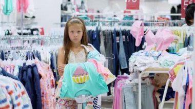 sıkıcı mağazalarda alışveriş. yorgun, üzgün çocuk, depodaki ebeveynler için bekleyen kız, ellerinde, şeylerin bir demet.