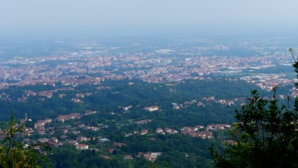 Ein schöner Blick von den Bergen auf eine kleine italienische Stadt am Fuße der Alpen. Heißer Sommertag. — Stockvideo