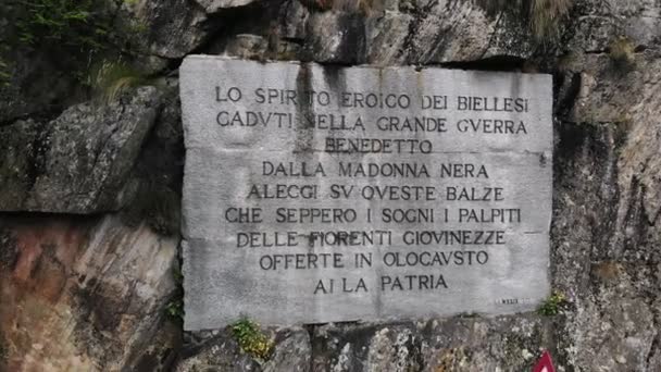 OROPA, BIELLA, ITALIA - 7 DE JULIO DE 2018: aero Vista de una hermosa inscripción grande sobre roca cerca del Santuario de Oropa, santuario ubicado en las montañas. Turistas caminando en parque en las montañas , — Vídeos de Stock