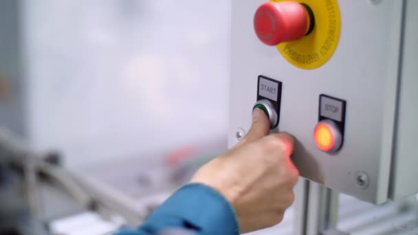Крупным планом, на специальном щите, рука нажимает зеленую кнопку запуска, рядом с красной остановкой — стоковое видео