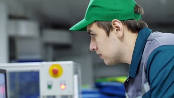 Retrato de um empregado de uma empresa, fábrica. um trabalhador olha para um monitor de computador, ajusta, controla o trabalho das máquinas, produção automatizada . — Vídeo de Stock