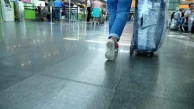 Havaalanı Boryspil, Ukrayna - 24 Ekim 2018: yakın çekim. Arkadan görünüm. spor ayakkabı kadın bacaklar. Kadın, Gezgin, yolcu ile sarılı çantası Bagaj Havaalanı salonu yürüyüş.