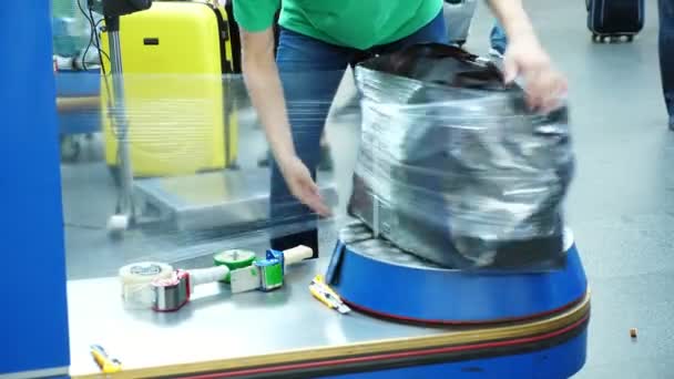 Упаковка багажа в аэропорту в целях безопасности и защиты от повреждений . — стоковое видео