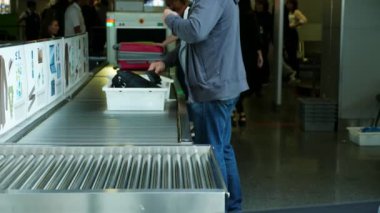 Havaalanı Boryspil, Ukrayna - 24 Ekim 2018: Erkek yolcu eşyalarını plastik tepsi, Bagaj, Havalimanı'nda el bagajı kontrol etmek için x-ray tarayıcı önünde bir konveyör bant sille koyar.