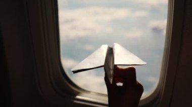 yakın çekim. Küçük kağıt uçak uçak penceresinin arka planı Childs'ın yardım silüeti. Uçak cam kenarında oturan ve küçük kağıt uçak ile oynayan çocuk. Uçuş sırasında uçakta