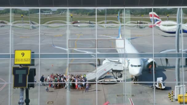 AIRPORT BORYSPIL, UKRAINE - OCTOBER 24, 2018: Ukraina International Airlines. penumpang Boarding pesawat dan bersiap-siap untuk penerbangan. Refleksi dari jendela bangunan bandara yang tercermin. Musim panas cerah — Stok Video