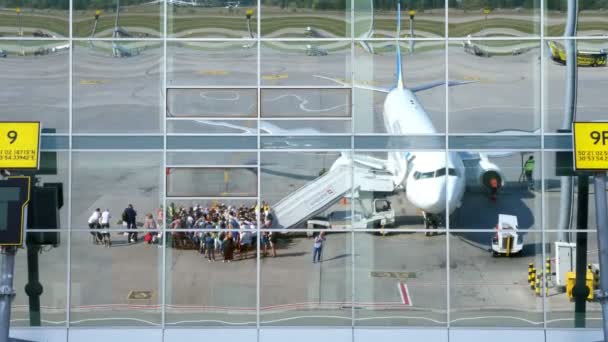 AIRPORT BORYSPIL, UKRAINE - OCTOBER 24, 2018: Ukraina International Airlines. penumpang Boarding dalam penerbangan dan bersiap-siap untuk terbang. Refleksi dari jendela bangunan bandara yang tercermin. Musim panas cerah — Stok Video